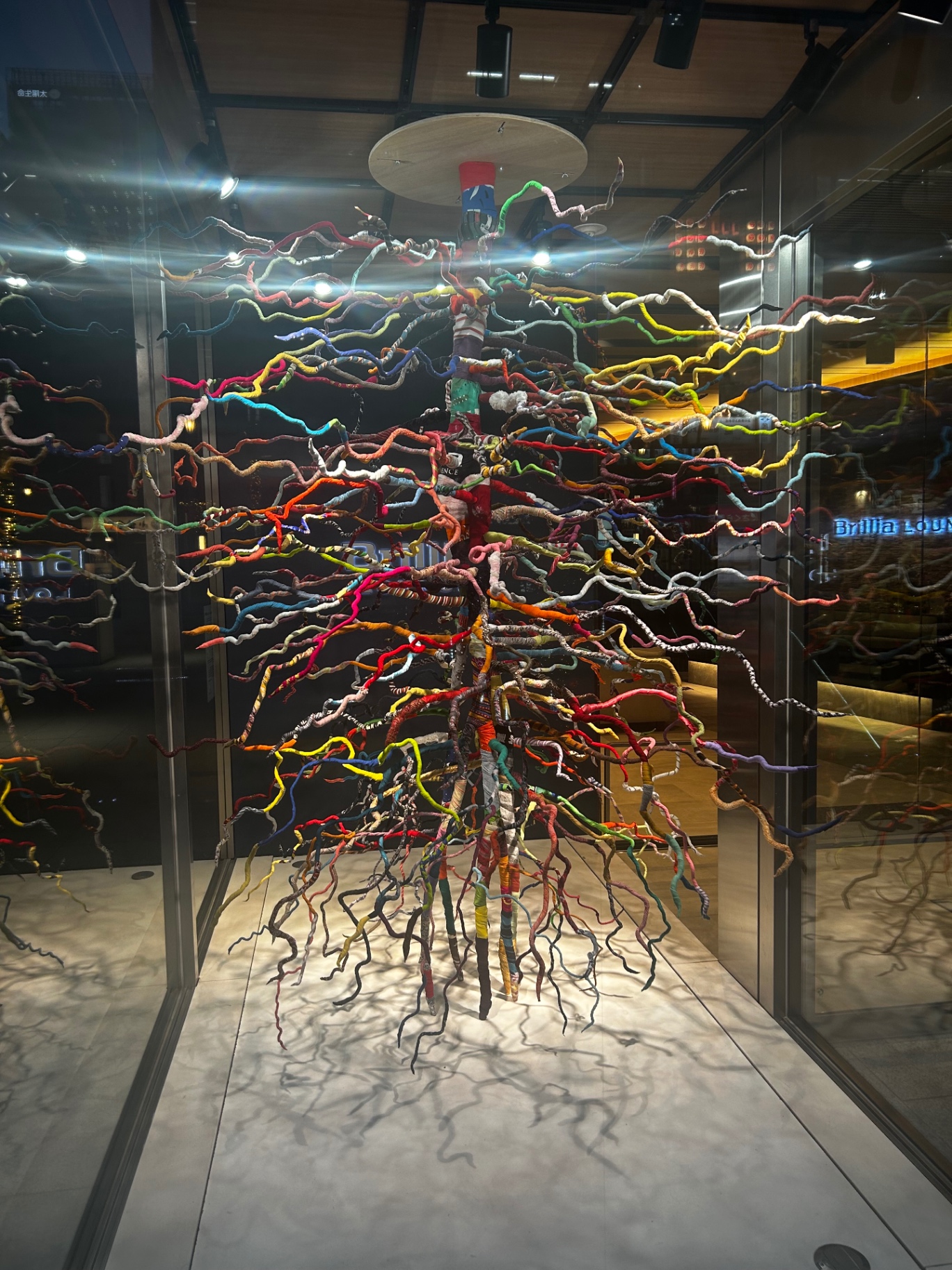Colorful woven sculpture suspended in a glass atrium