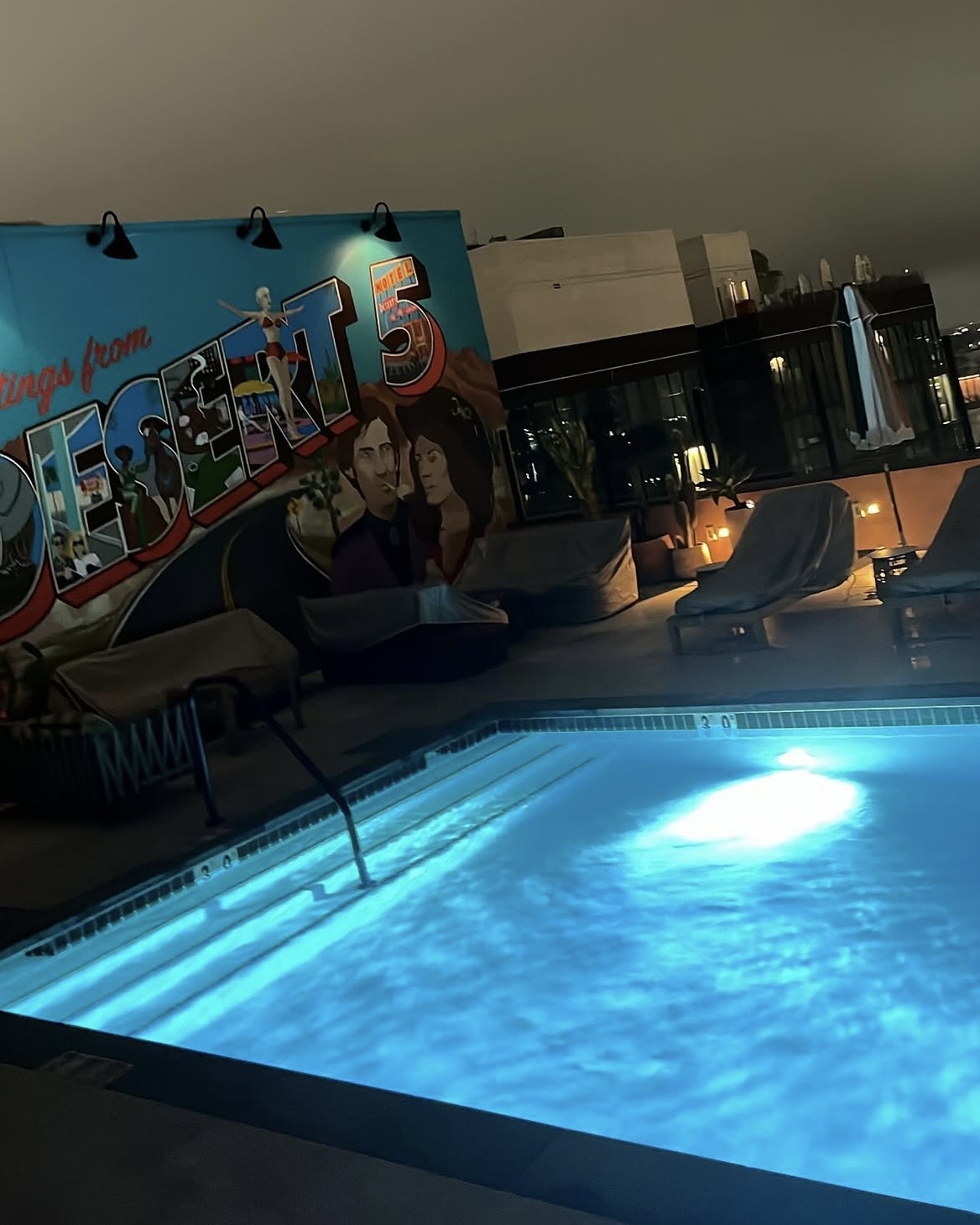 Rooftop pool with Desert 5 mural at night