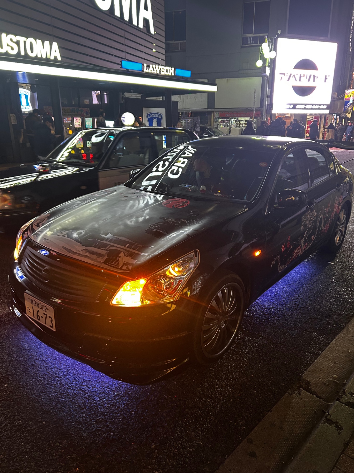 Custom Nissan sedan on a Tokyo street at night